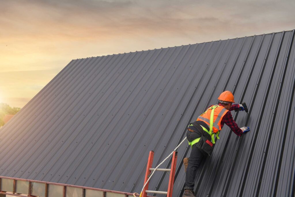 Professional metal roof contractor screws in rivets on metal roof